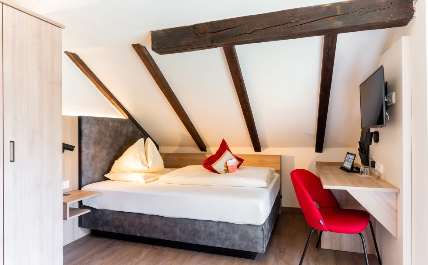 Einzelzimmer mit Schreibtisch, Dachbalken und wohnlichem Ambiente in Salzburg